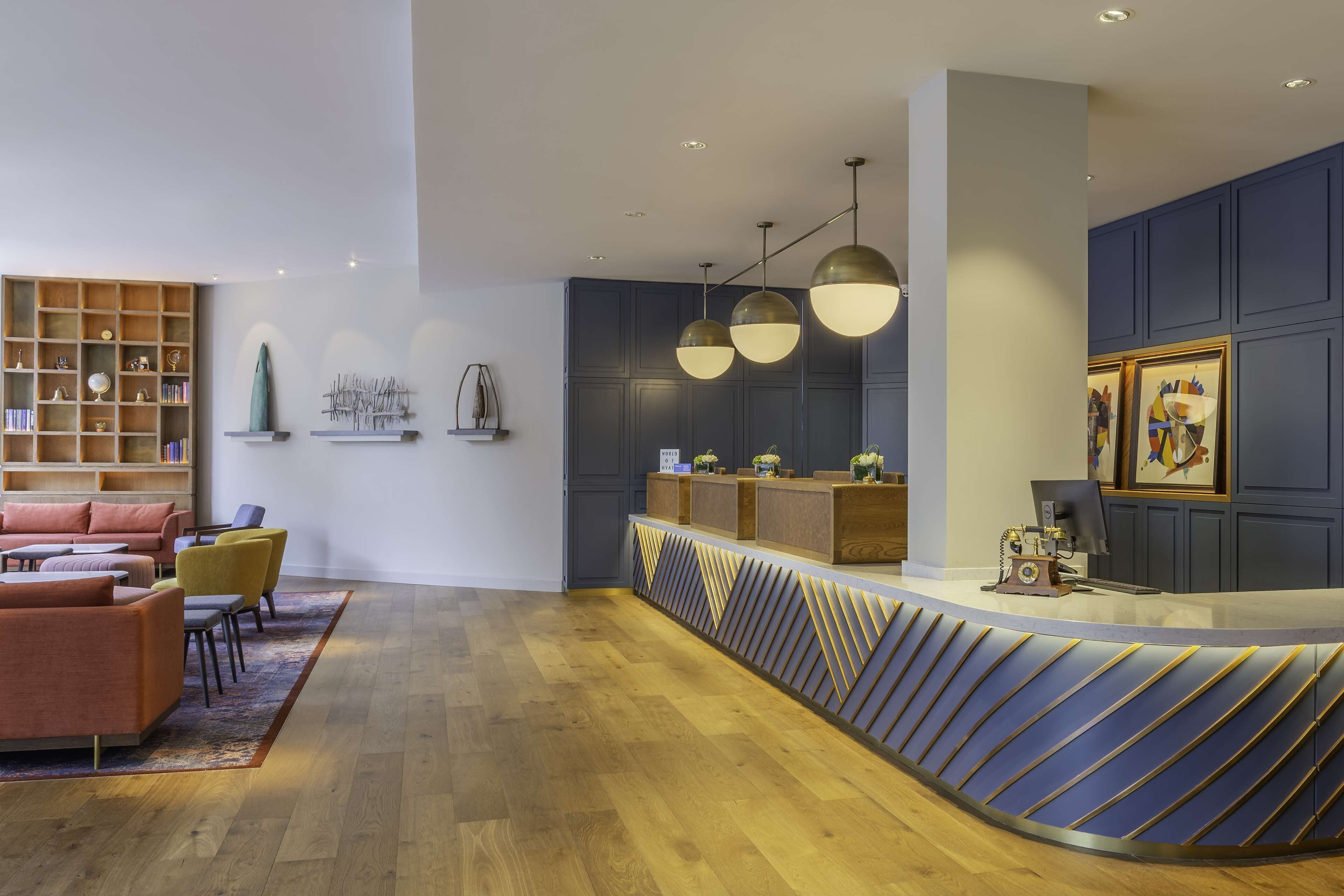 A modern reception area with a curved counter, wooden flooring, and a seating area with sofas and chairs.