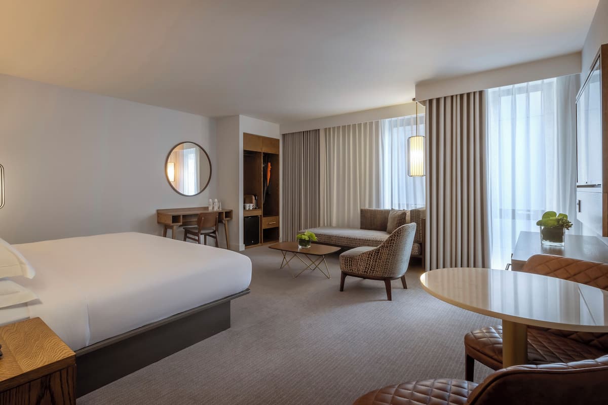 Een hotelkamer met een groot bed, een bureau, een stoel, een kleine tafel en een bank.