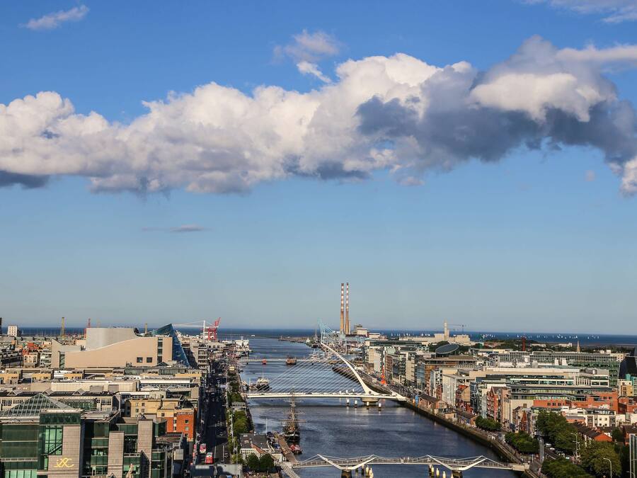 Un paisaje urbano con un puente destacado, edificios modernos y un río.
