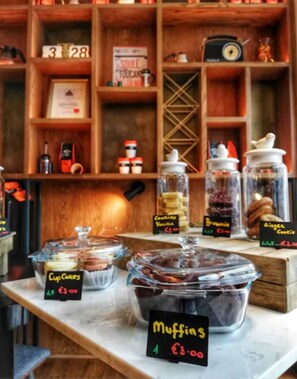 A bakery display with labeled items like Cupcakes, Muffins, Cookies, Brownie, and Ginger Cookie. - Hyatt Centric The Liberties Dublin (Dublin)