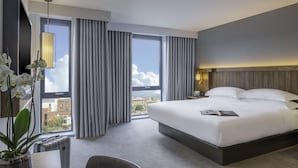 Een moderne hotelkamer met een groot bed, uitzicht op de stad en een potorkidee.