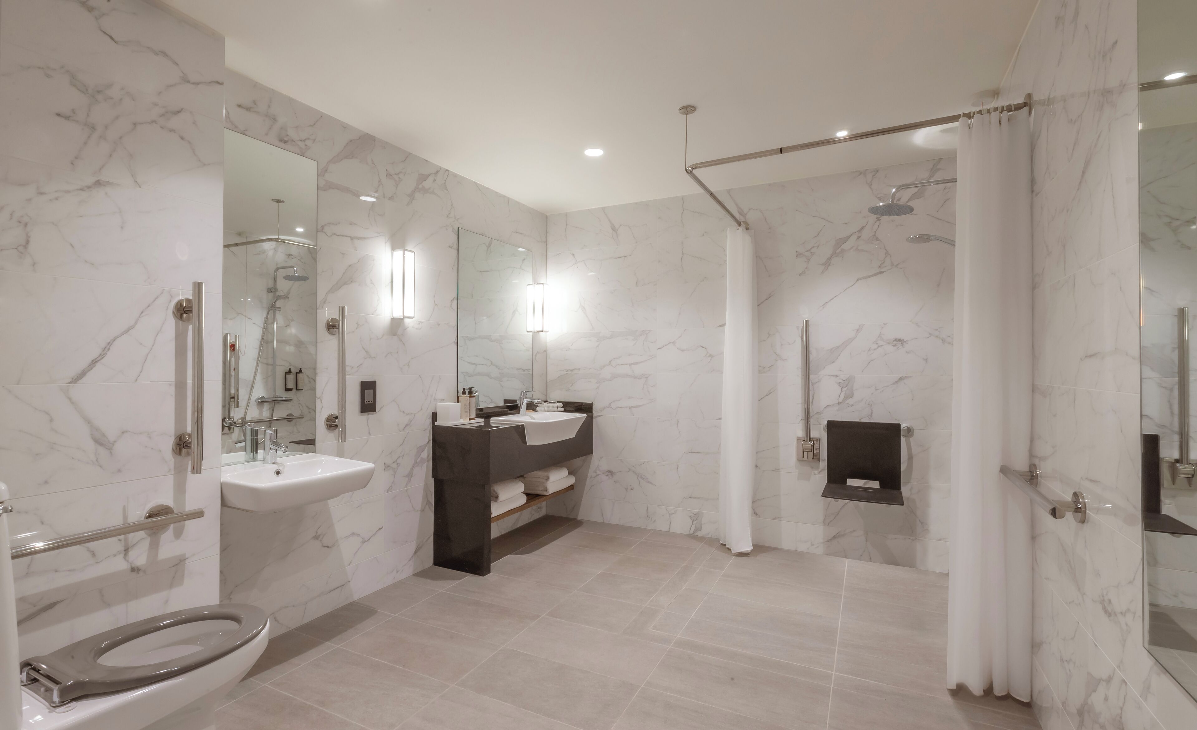 A modern bathroom with a marble floor, a sink, a toilet, a shower with a glass door, and a mirror.