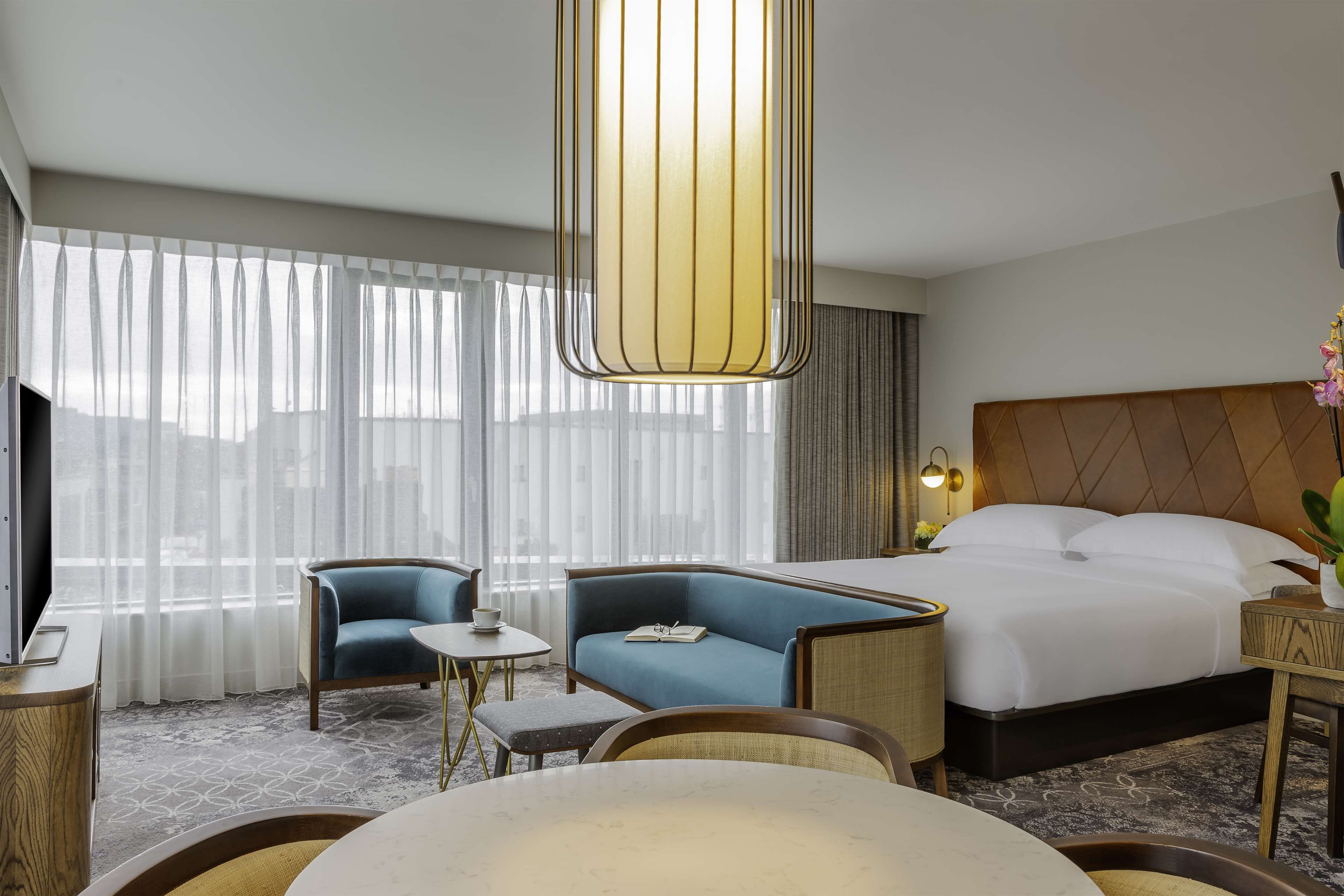 Ein Hotelzimmer mit einem großen Bett, einer Couch, einem kleinen Tisch und einem Fernseher.