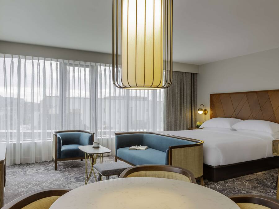Ein Hotelzimmer mit einem großen Bett, einer Couch, einem kleinen Tisch und einem Fernseher.