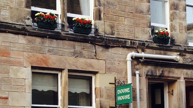 A stone building with a green sign reading "Dounie House." There are flower boxes on the windows and a door with a sign above it. - Doune Guest House (St. Andrews)
