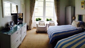 A bedroom with two beds, a desk, a chair, a wardrobe, and a window with curtains. - Doune Guest House (St. Andrews)