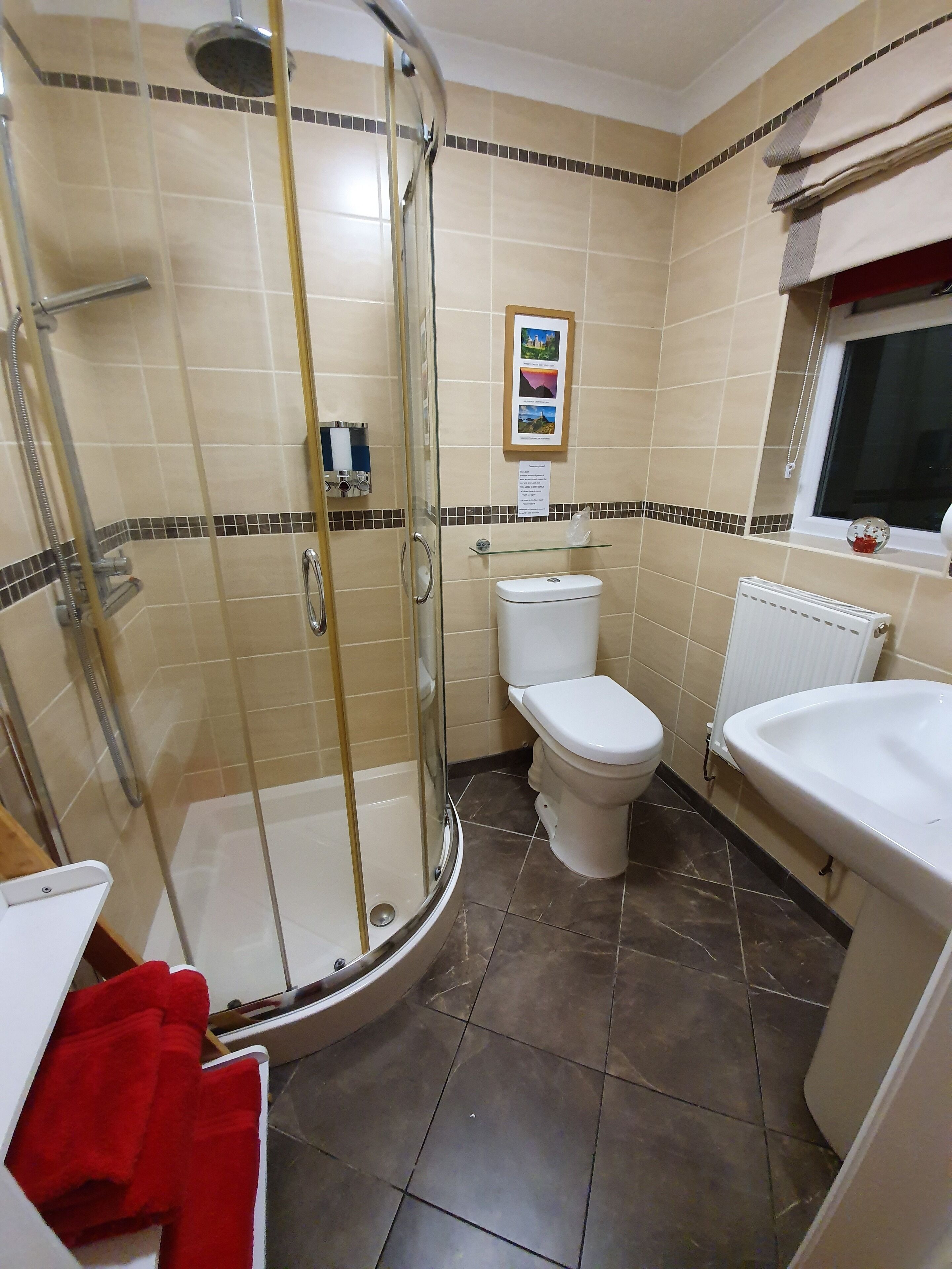 A bathroom with a glass-enclosed shower, a toilet, and a sink.