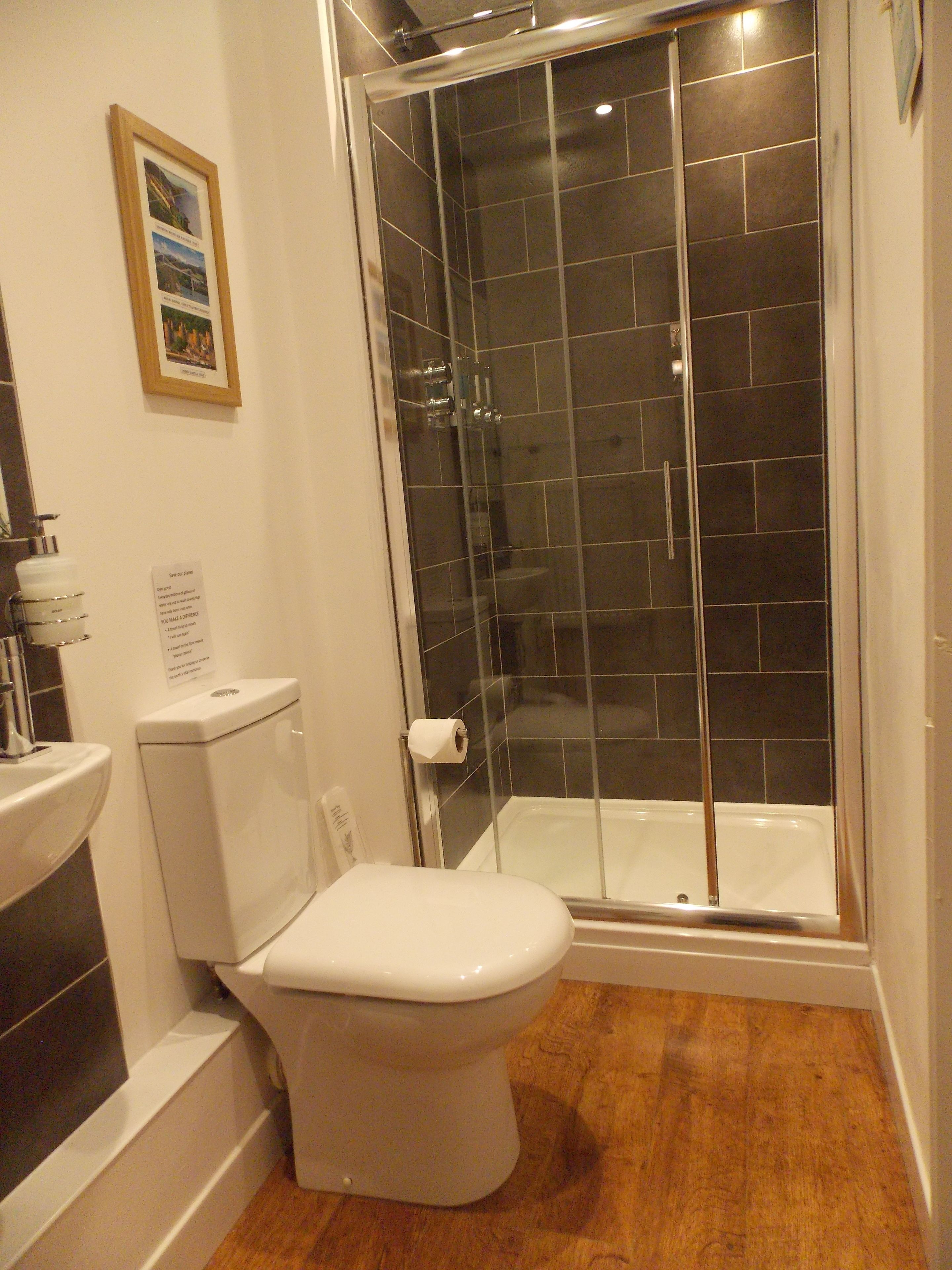 Une salle de bain comprenant des toilettes, un lavabo, une douche en verre et un tableau encadré au mur.