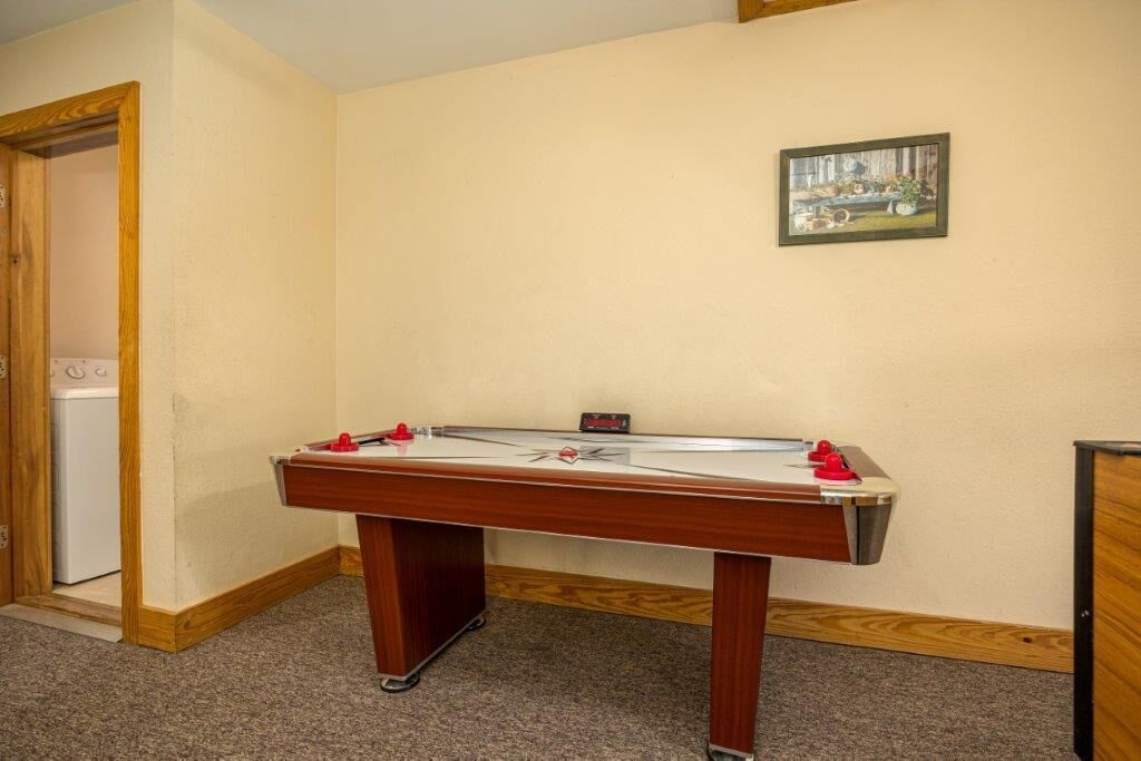 A room with a foosball table, a door leading to a laundry area, and a framed picture on the wall.