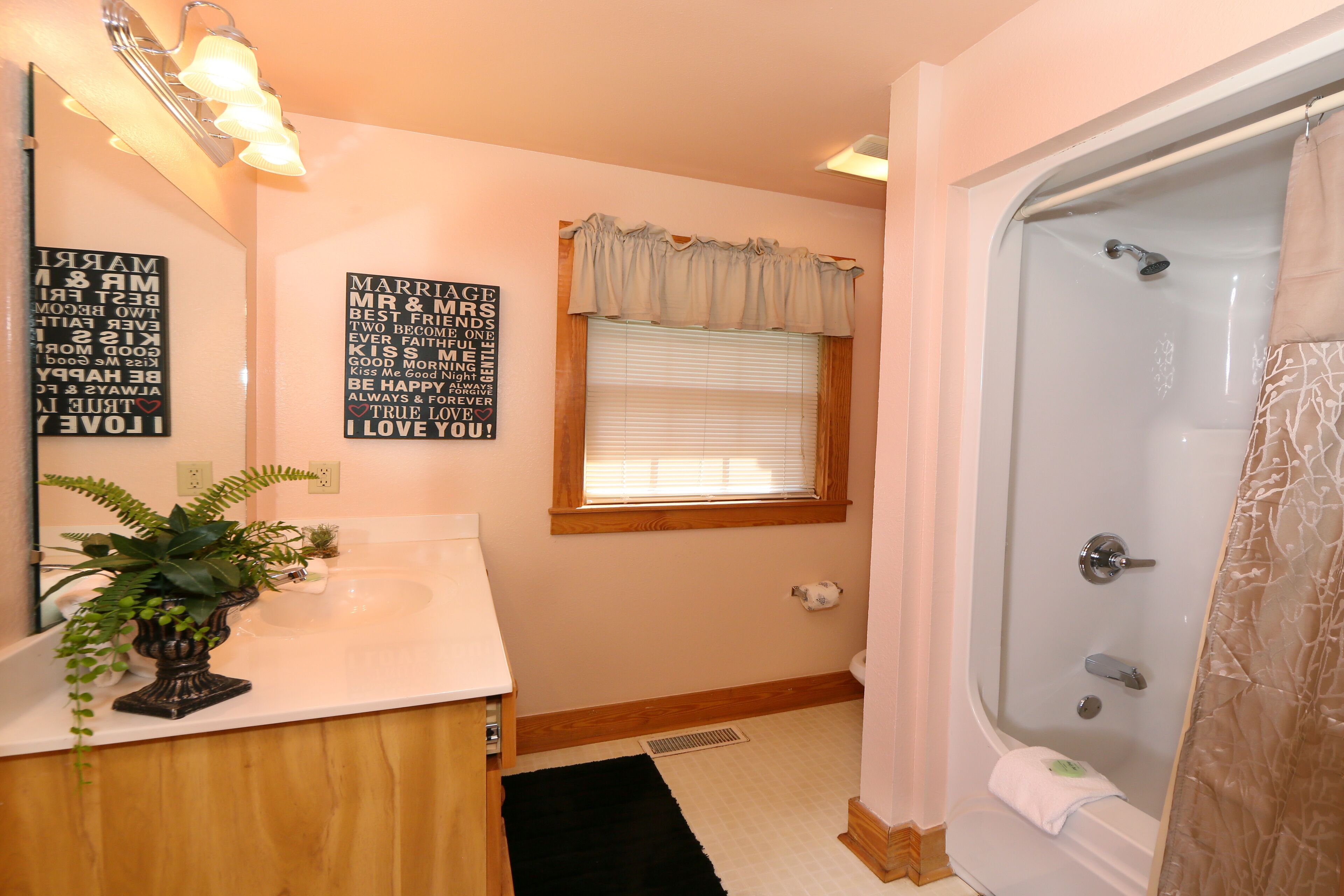 Un baño con bañera, lavamanos, espejo y ventana con cortina.