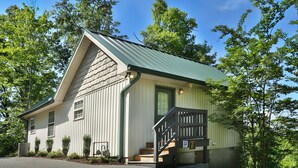 A building with a green roof, a front porch, and a staircase leading to the entrance.