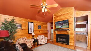 A cozy living room with a fireplace, a television mounted on the wall, and a comfortable seating area.