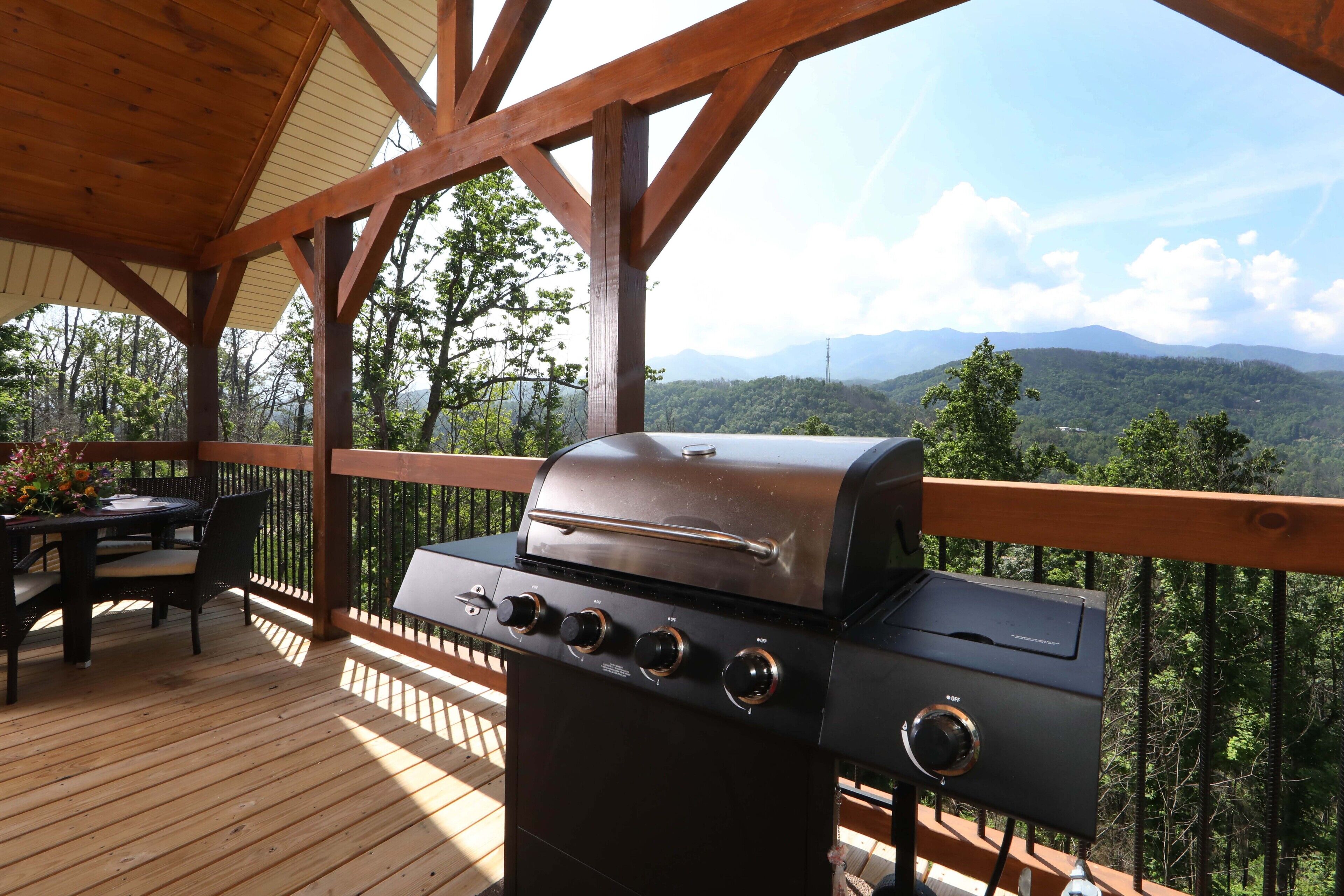 Un espace extérieur abrité comprenant un barbecue, une terrasse en bois et une table avec des chaises.