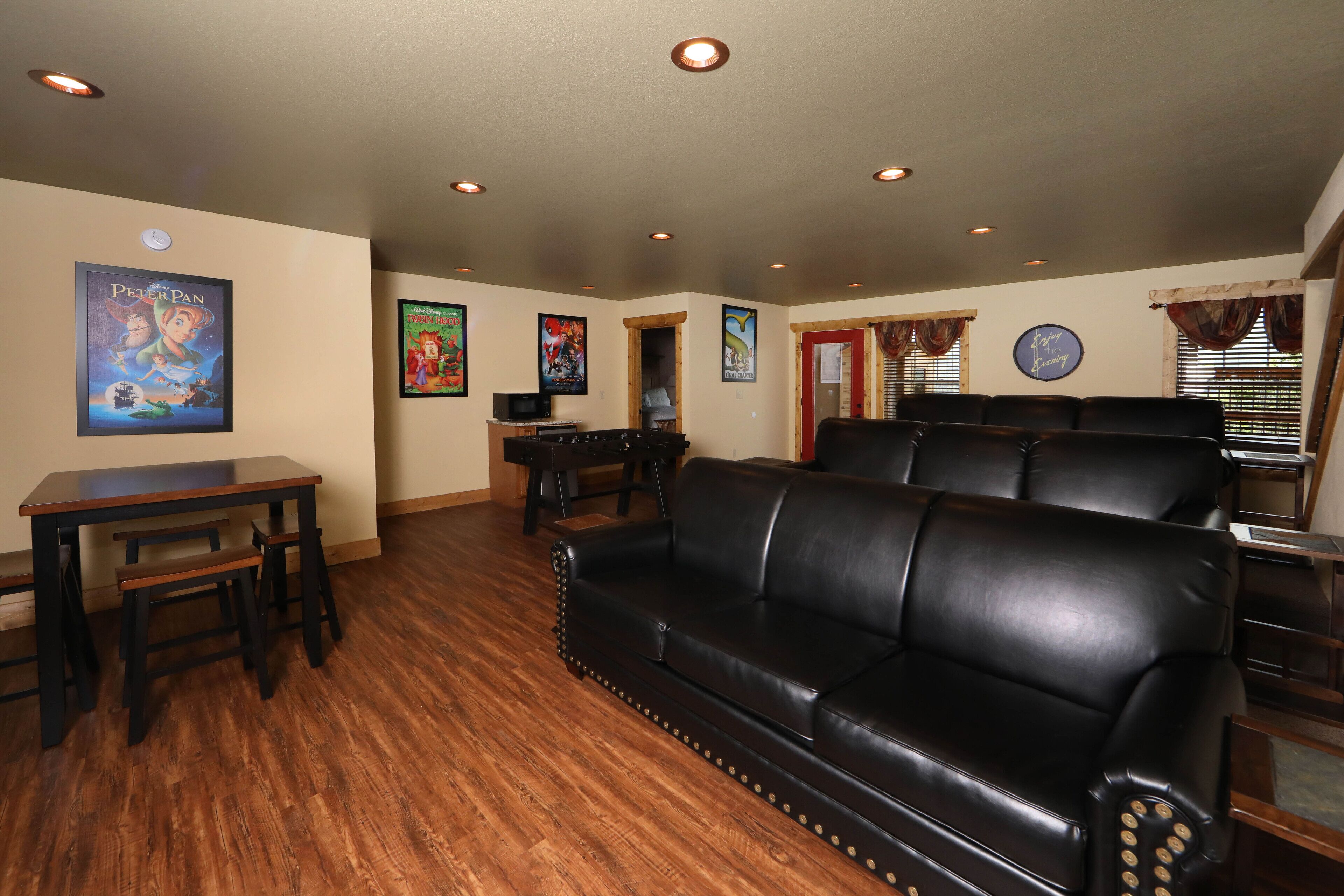 A living room with a black leather sofa, wooden coffee table, and a television.