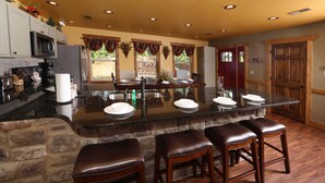 A kitchen with a central island, bar stools, a microwave, and a refrigerator. - Above It All - Four Bedroom Cabin (Gatlinburg)