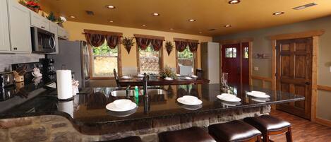A kitchen with a central island, bar stools, a microwave, and a refrigerator.