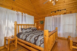 Cozy bedroom with a central bed, wooden nightstand, and a ceiling fan.