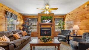 Una sala de estar acogedora con chimenea, sofá de cuero y ventilador de techo.