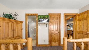 Una habitación con muebles de madera, una cama, una puerta de madera y vista a una zona de cocina.
