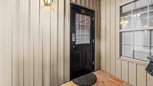 Una puerta negra con un cartel de 'WAIT', un buzón y una ventana con persianas.