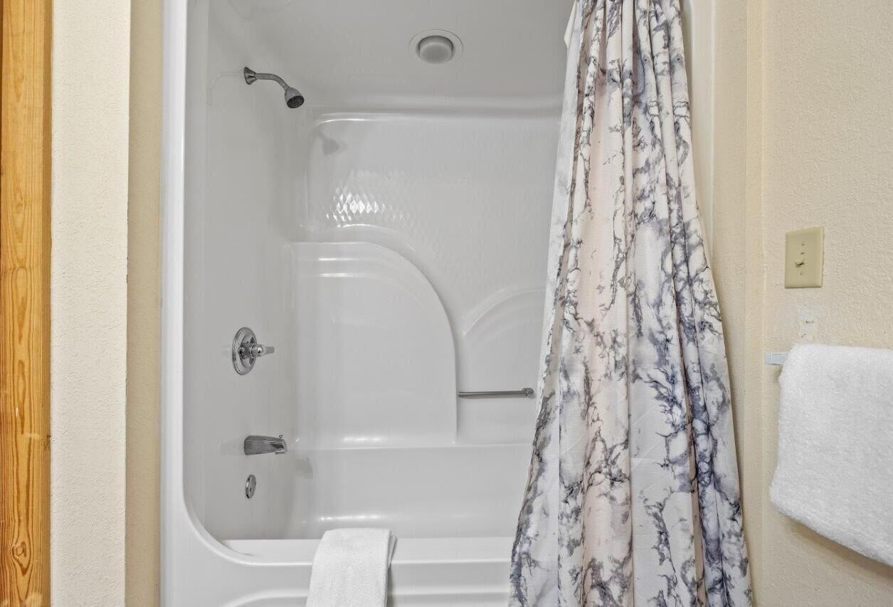 A bathroom with a bathtub, shower, and a towel rack.