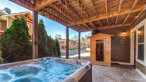 A hot tub under a wooden pergola with stone flooring, surrounded by a residential neighborhood. - Aqua Paradise - Six Bedroom Chalet (Gatlinburg)