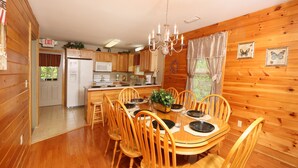 A wooden cabin interior with a dining area, kitchen, and an exit sign. - Pinnacle View 7A - Three Bedroom Chalet (Pigeon Forge)