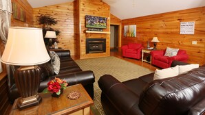 A cozy living room with a fireplace, leather sofas, and a television mounted on the wall. - Pinnacle View 7A - Three Bedroom Chalet (Pigeon Forge)