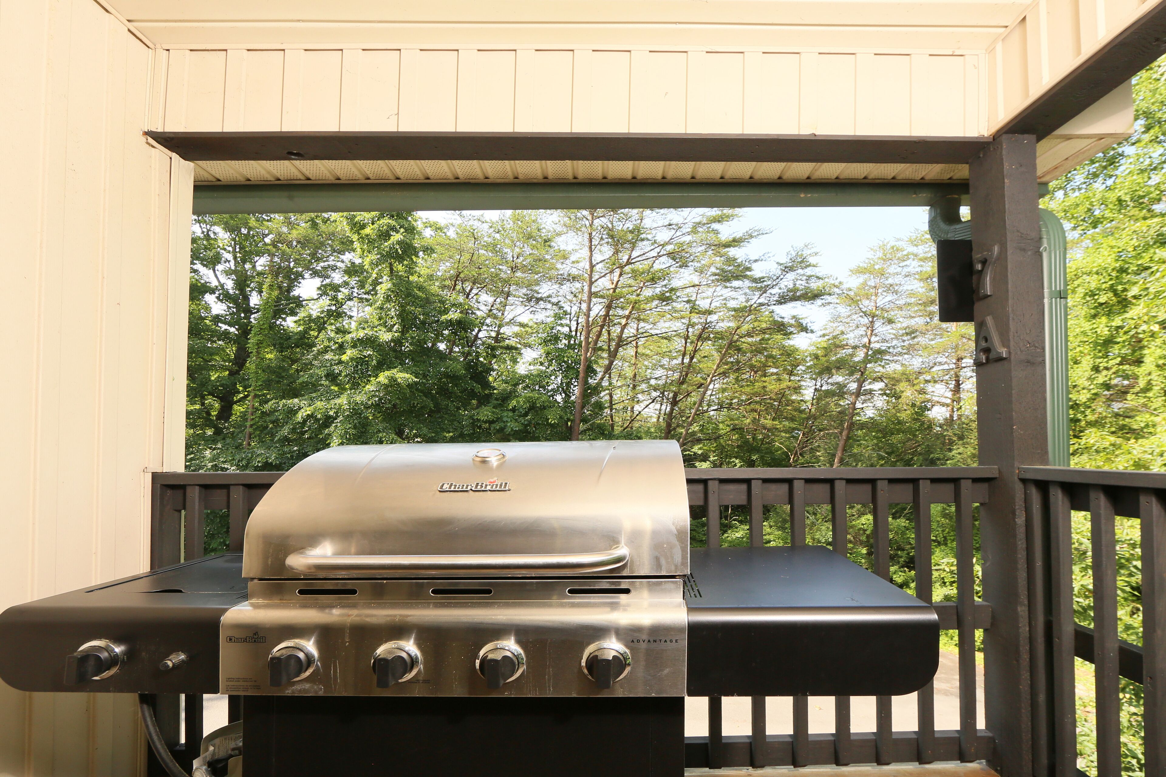 Un barbecue Char-Broil installé sur une terrasse extérieure, avec vue sur les arbres.