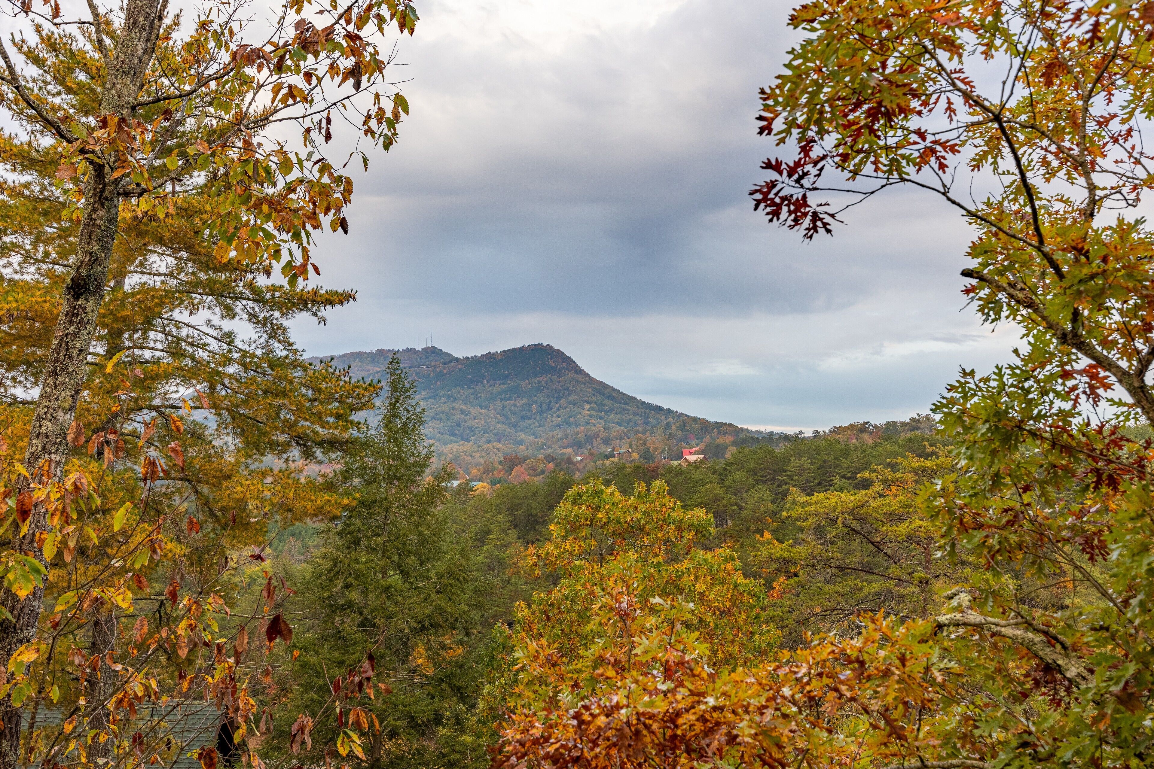 A mountainous landscape with autumn foliage and a cloudy sky.