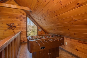 Relax in this inviting room with a foosball table and a unique bird-inspired wall piece, offering a view of the outdoors.