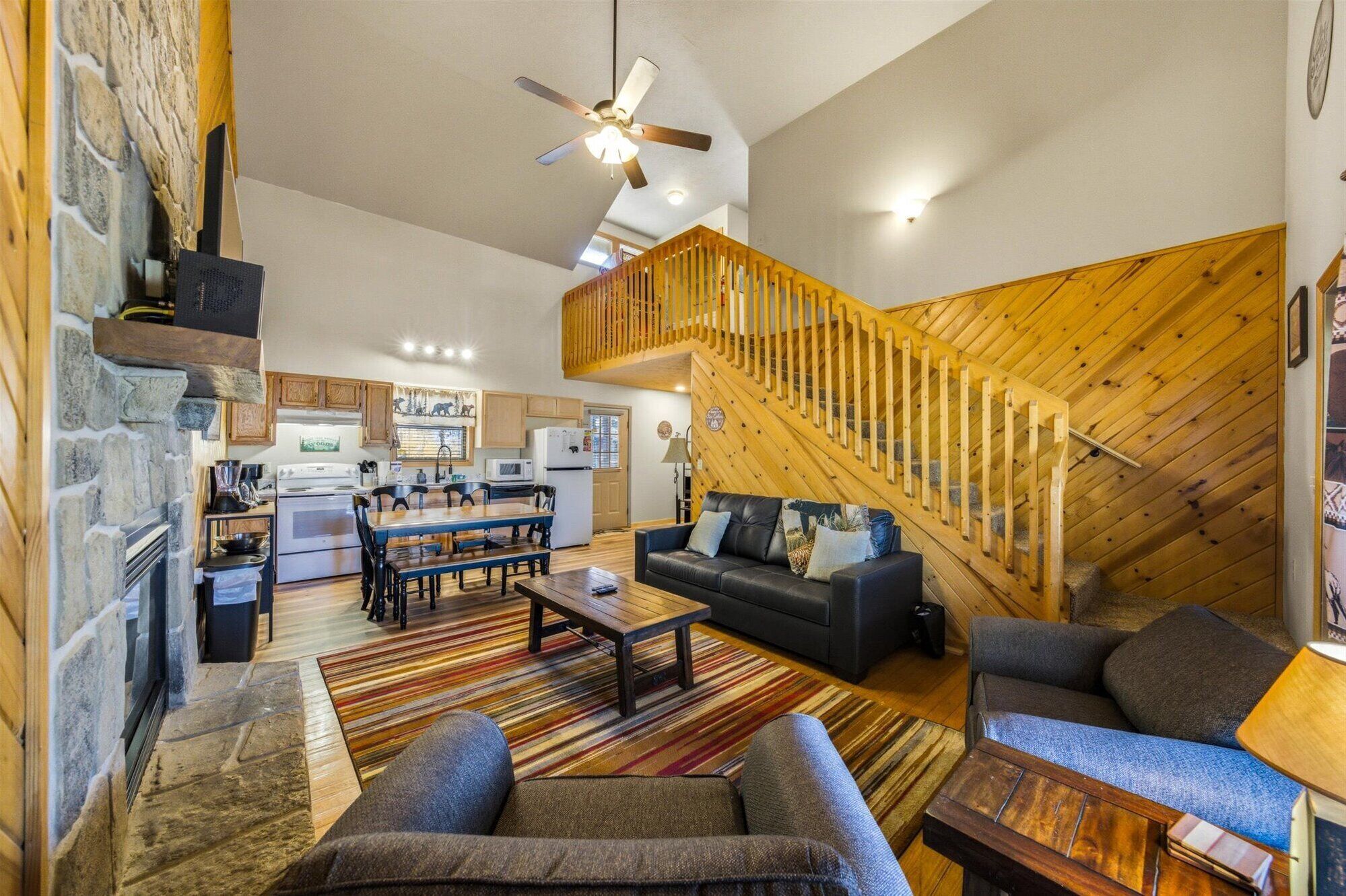 A spacious living area with a fireplace, a dining table, sofas, and a staircase.