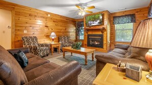 A cozy log cabin interior with a fireplace, wooden walls, and comfortable seating. - Poplar Point Condo Unit 12E - Three Bedroom Condo (Pigeon Forge)