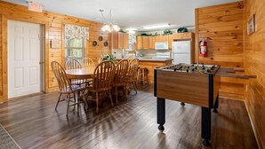 A cozy wooden cabin with a dining area, kitchen, and a foosball table. - Poplar Point Condo Unit 12E - Three Bedroom Condo (Pigeon Forge)