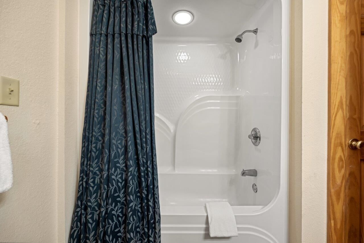 Une salle de bain avec une baignoire, une douche et un rideau.