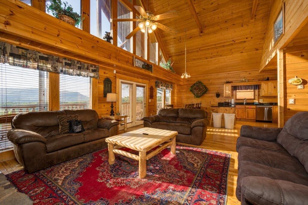 A cozy cabin interior with two sofas, a wooden coffee table, and a kitchen area.