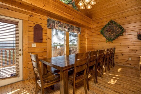 Interior de madera con una mesa y sillas de comedor, una ventana con persianas y un adorno en la pared.