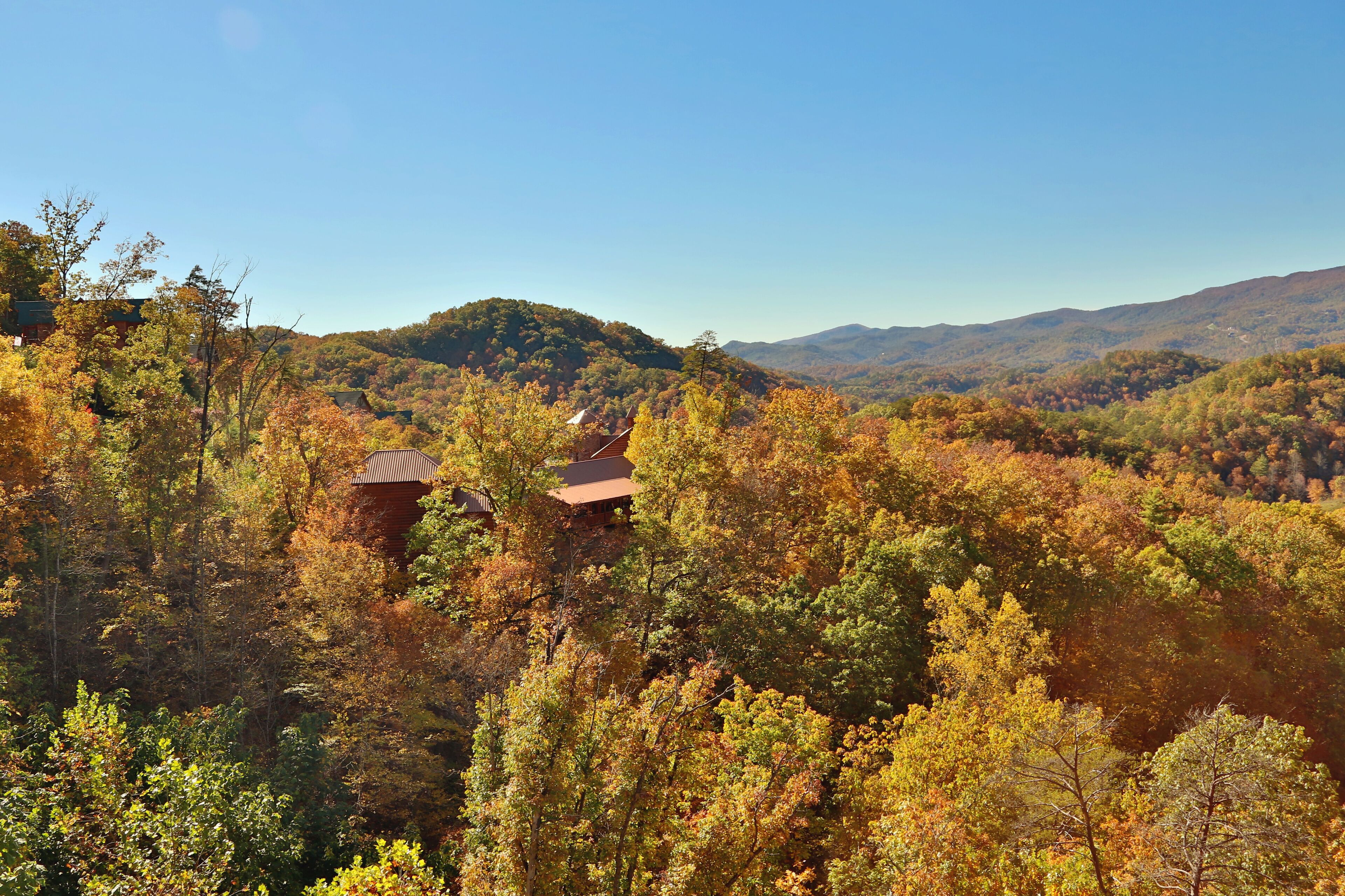 A mountainous landscape with autumn foliage and two rustic cabins.