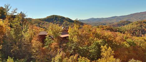 A mountainous landscape with autumn foliage and two rustic cabins.