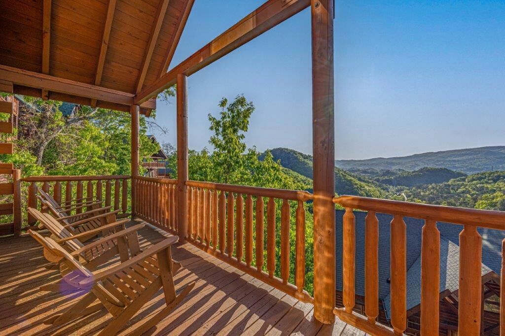 A wooden deck with a railing overlooking a mountainous landscape.