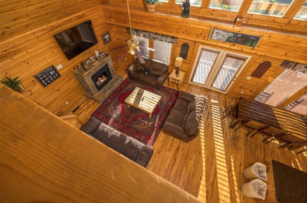 A cabin interior with a fireplace, seating area, and a large window.