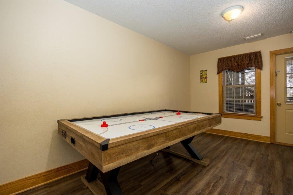A room with a wooden floor, a white wall, and a door with a window.