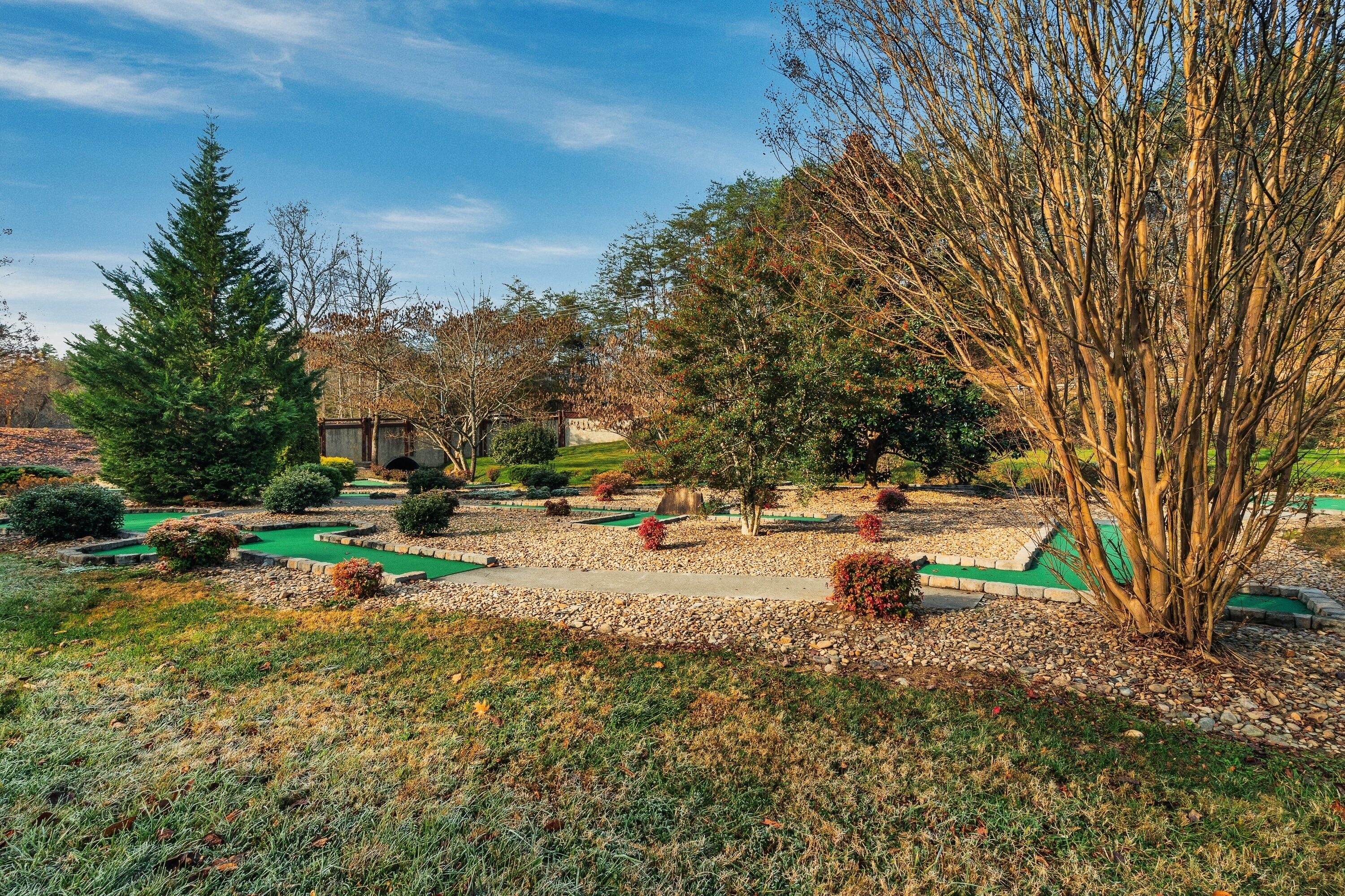 A golf course with a putting green, trees, and a building in the background.