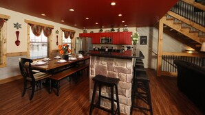 Una cocina amplia con armarios rojos, una isla de piedra y una escalera de madera.