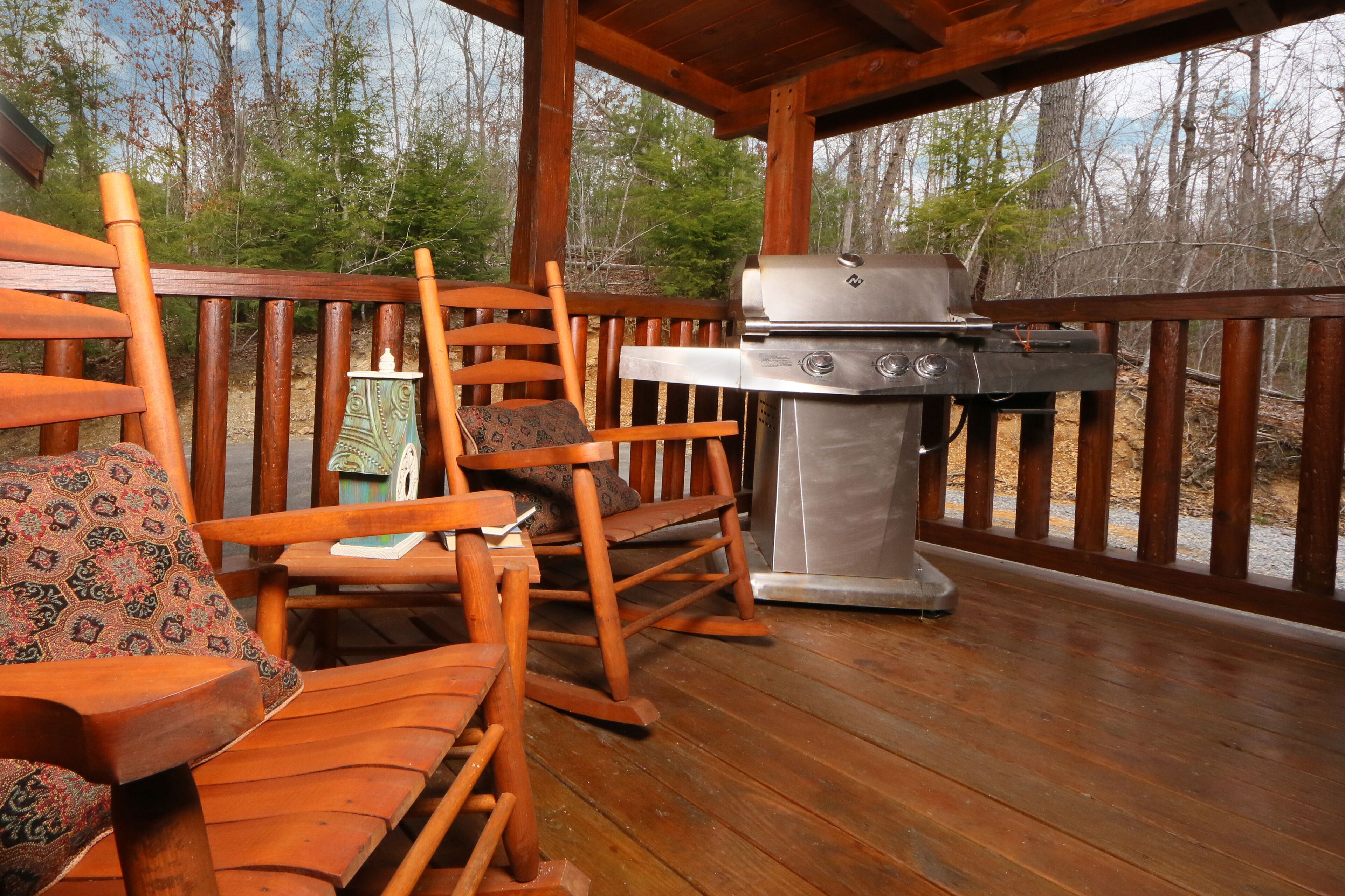Une terrasse en bois avec un barbecue et des fauteuils à bascule.
