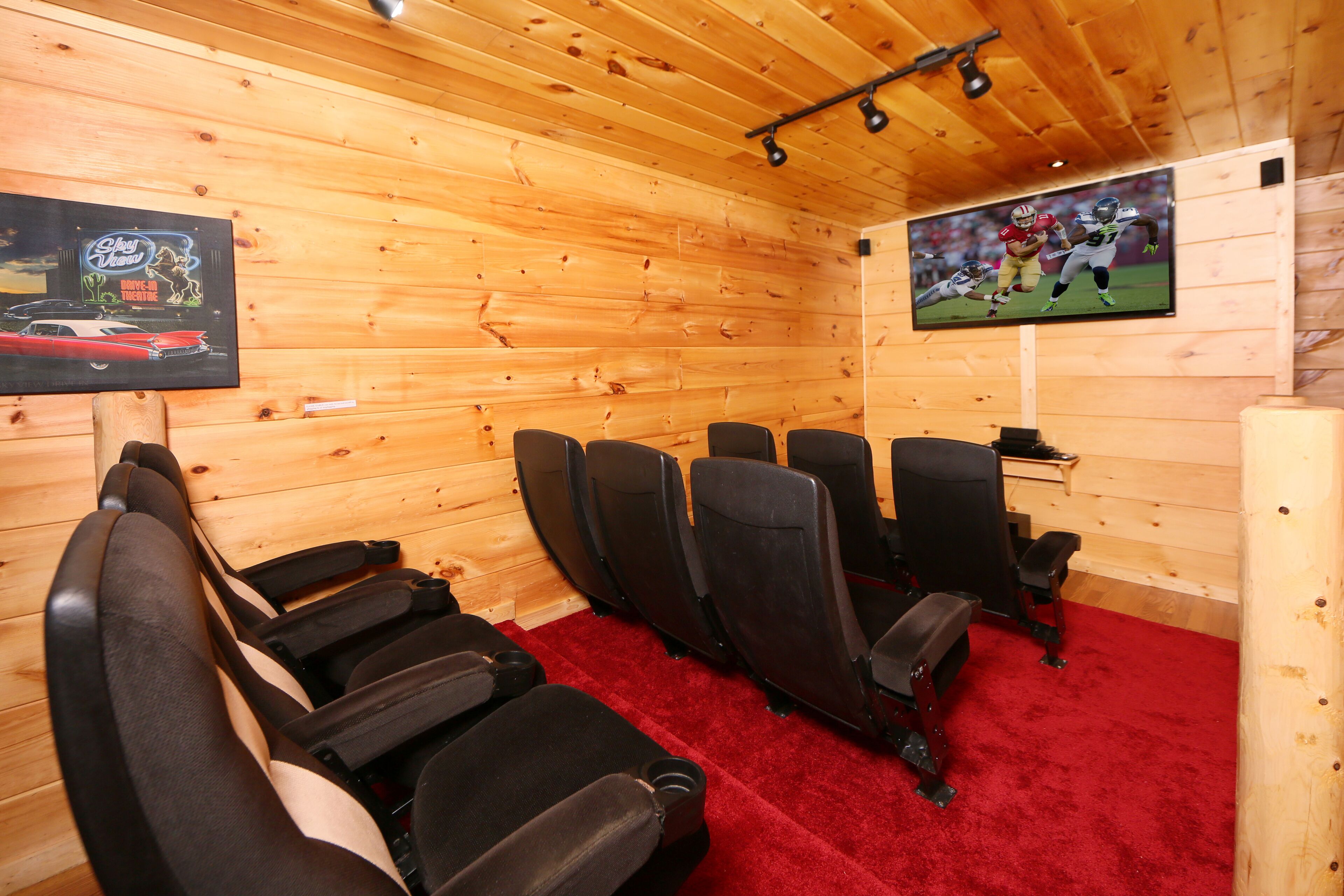 A room with wooden walls and ceiling, a red carpet, and multiple black chairs arranged in rows.