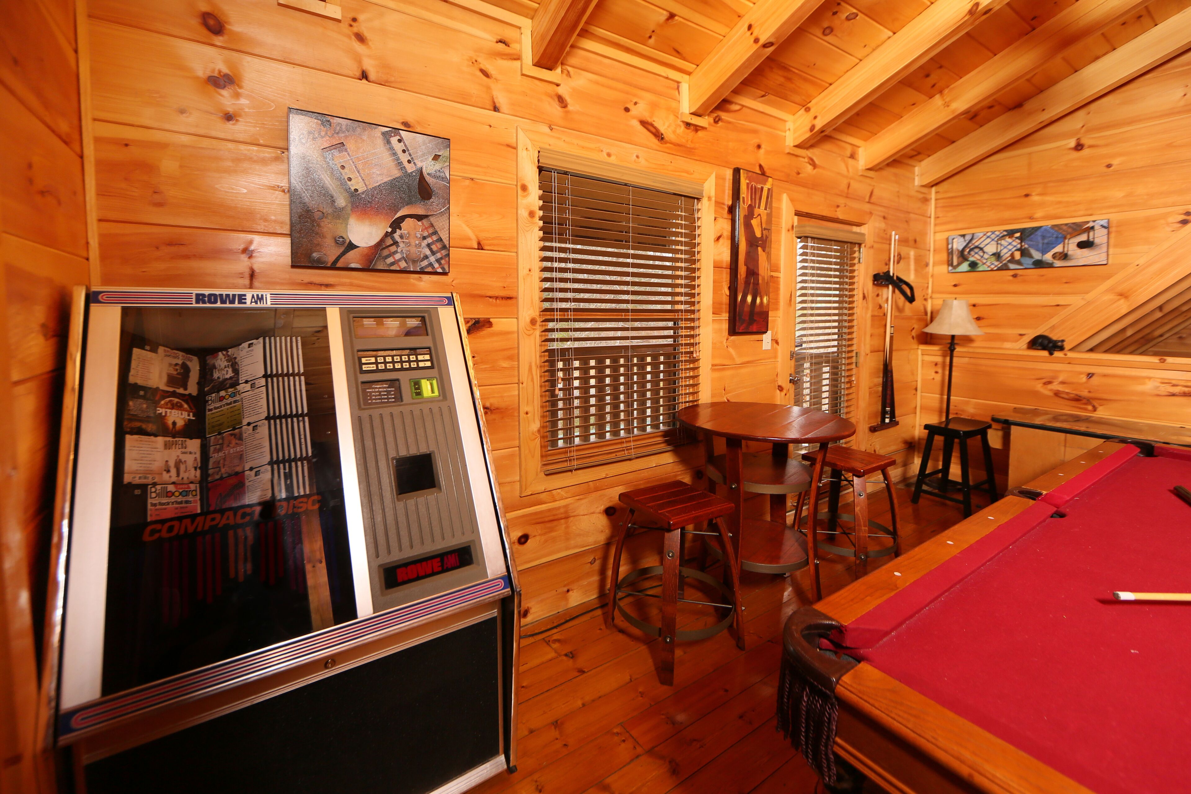 Een houten interieur met een pooltafel, barstoelen en een jukebox.
