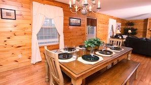 A wooden-paneled dining room with a wooden table set for four, a chandelier, and a framed 'LOVE' sign on the wall. - Pinnacle View 7C - Three Bedroom Chalet (Pigeon Forge)