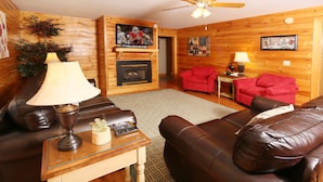 A cozy living room with a fireplace, leather sofas, a TV, and a ceiling fan. - Pinnacle View 7C - Three Bedroom Chalet (Pigeon Forge)