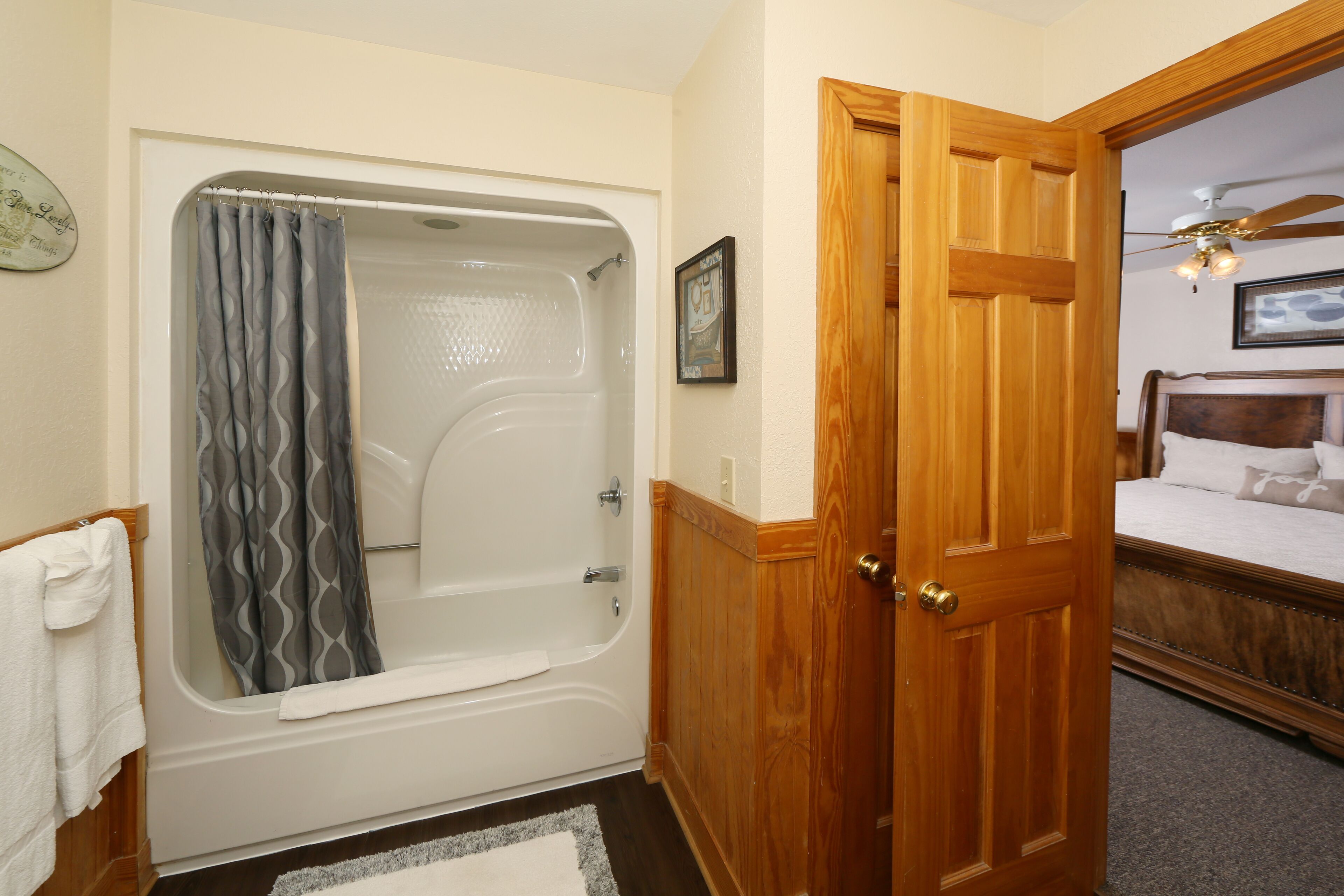 A bathroom with a bathtub, a wooden door, and a bed with a headboard.
